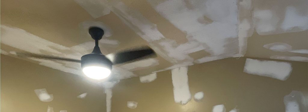 Ceiling drywall repair and joint compound prep around a ceiling fan fixture.