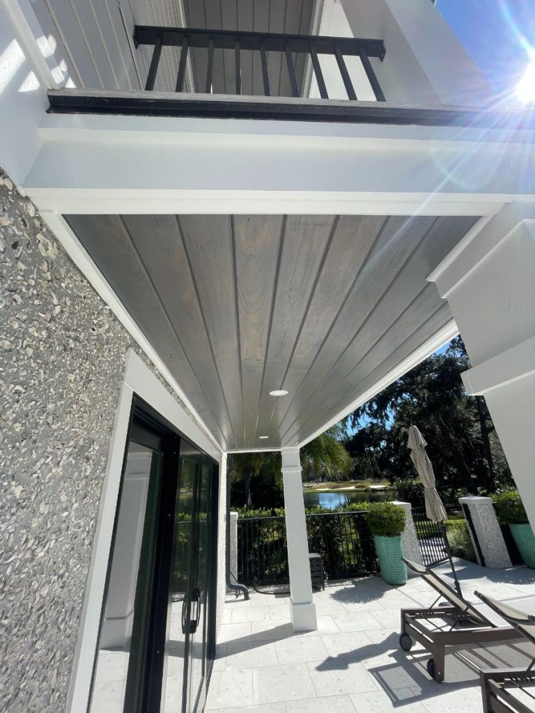 Covered outdoor patio with grey-stained wood ceiling tongue-and-groove paneling and white trim by Simons Painting & Drywall in Connecticut.
