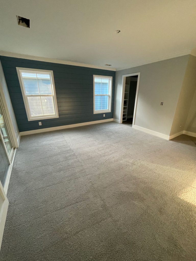 Spacious carpeted room with newly painted dark blue-gray accent walls, white trim, and doors by Simons Painting & Drywall in Connecticut.