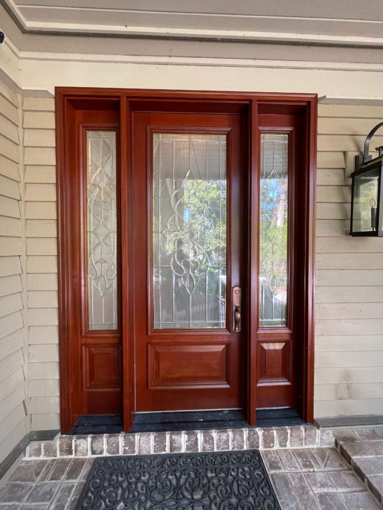 Rich wood-stained front entrance door with a protective clear coat finish by Simons Painting & Drywall.