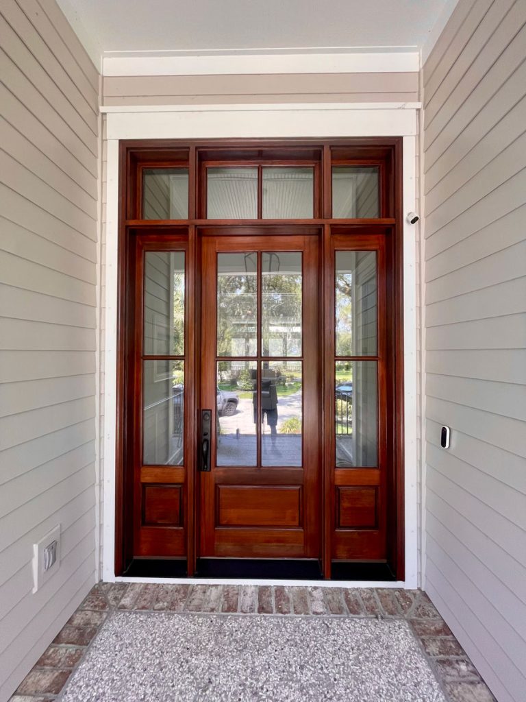 Stained mahogany wood entry door with glass panes and clear coat finish.