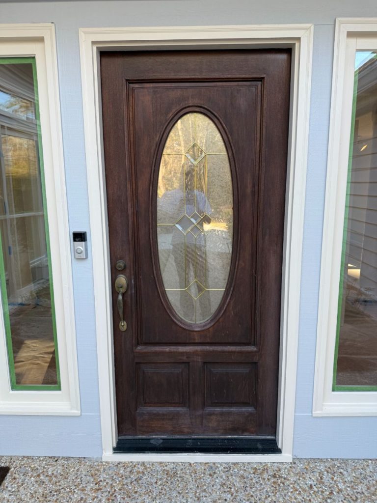 Refinished dark wood oval glass front door with green trim, completed
