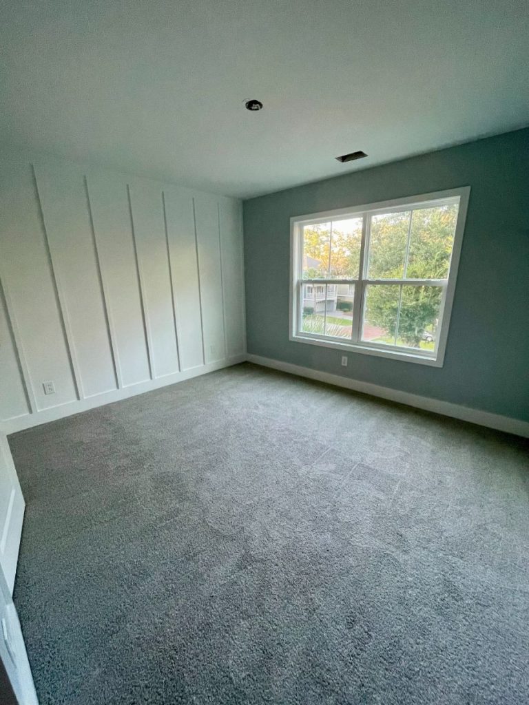 Bedroom featuring a custom floor-to-ceiling vertical board and batten feature wall painted in light blue-gray