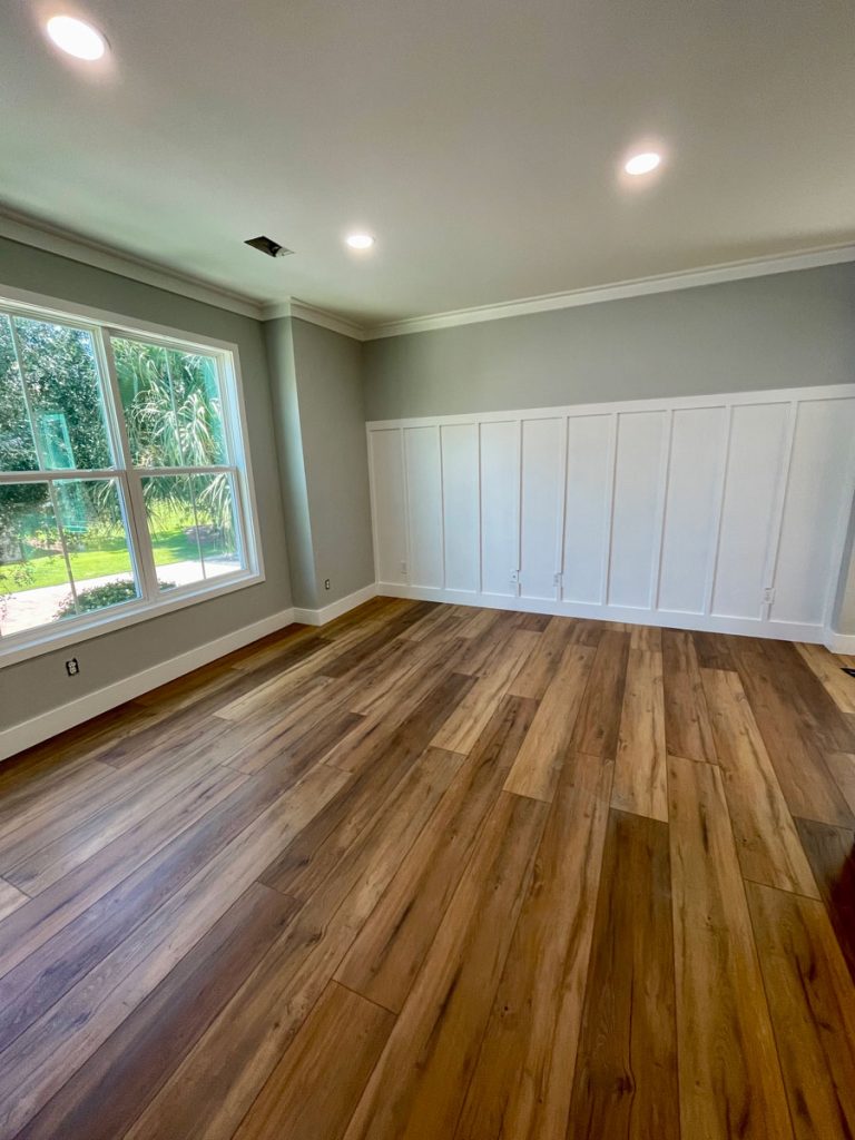Spacious room featuring floor-to-ceiling white board and batten accent wall paneling and hardwood floors