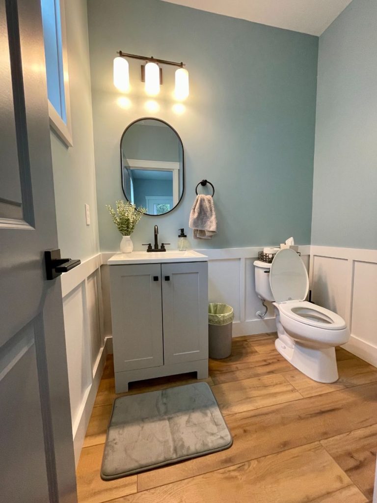 Bathroom with white wainscoting lower wall paneling and light blue painted upper walls