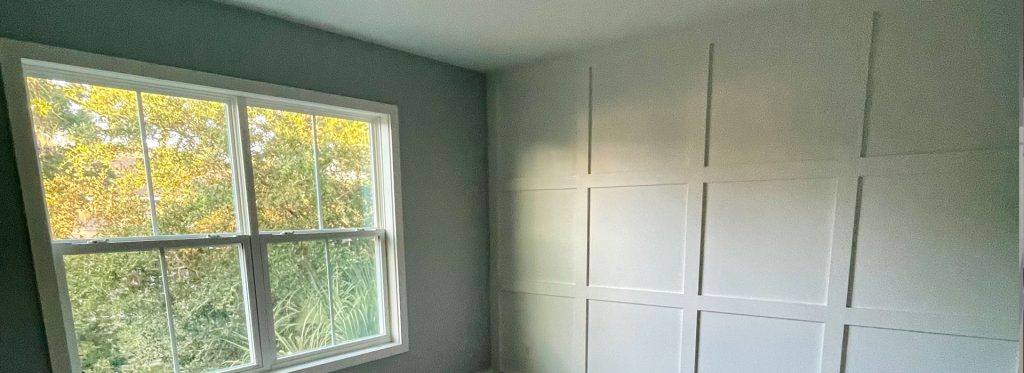 Custom white grid picture frame molding accent wall paired with soft gray painted walls